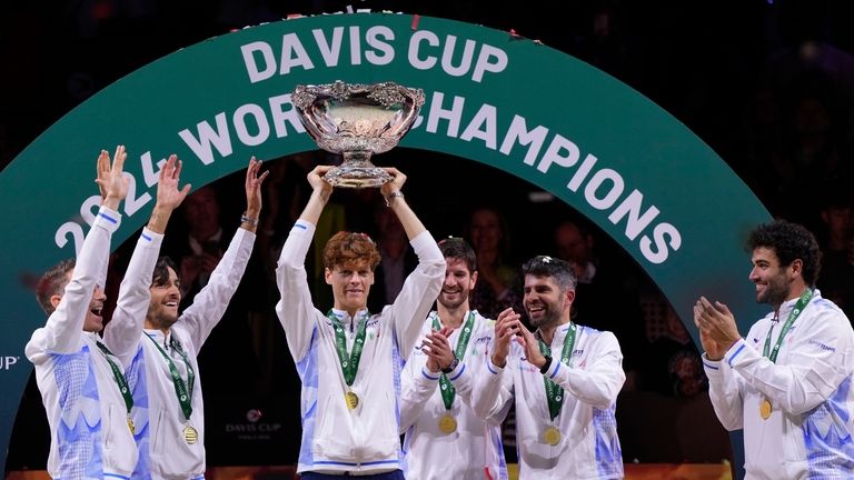 El italiano Jannik Sinner, centro, sostiene el trofeo de la Copa Davis junto a...