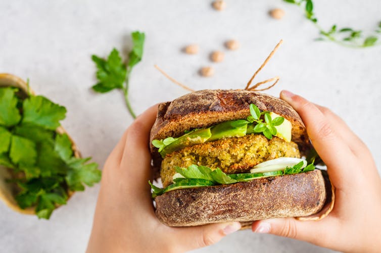 Persona con hamburguesa vegetal en la mano