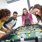 Hombres y mujeres jóvenes jugando futbolín