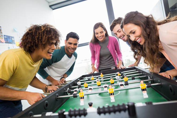 Hombres y mujeres jóvenes jugando futbolín